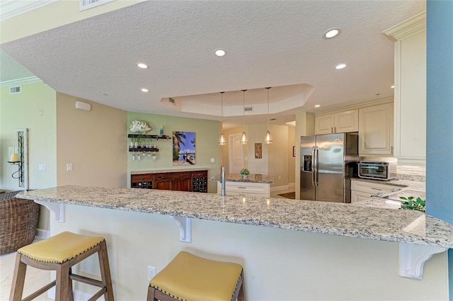 7820 34th Ave W Unit 102, Bradenton, FL 34209 - kitchen with stainless steel refrigerator with ice dispenser, a tray ceiling, light stone countertops, a kitchen breakfast bar, and recessed lighting