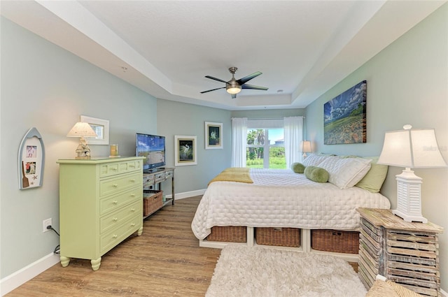 7820 34th Ave W Unit 102, Bradenton, FL 34209 - bedroom with a raised ceiling, light wood-type flooring, and a ceiling fan