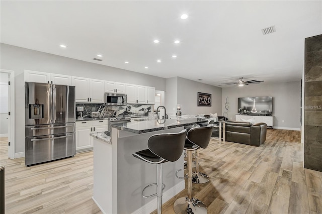 2912 51st St E, Bradenton, FL 34208 - kitchen featuring appliances with stainless steel finishes, light wood-style floors, a kitchen breakfast bar, white cabinetry, and ceiling fan