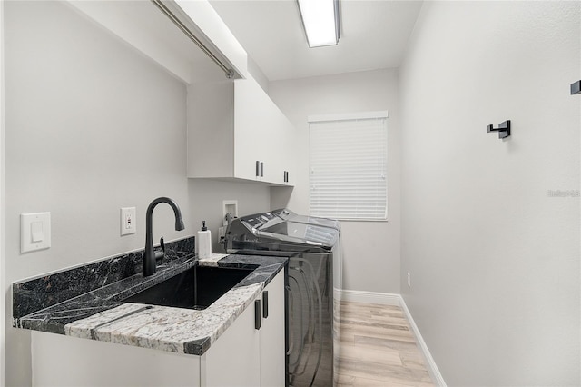 2912 51st St E, Bradenton, FL 34208 - kitchen featuring washer and clothes dryer, light wood-style floors, white cabinets, and light stone counters