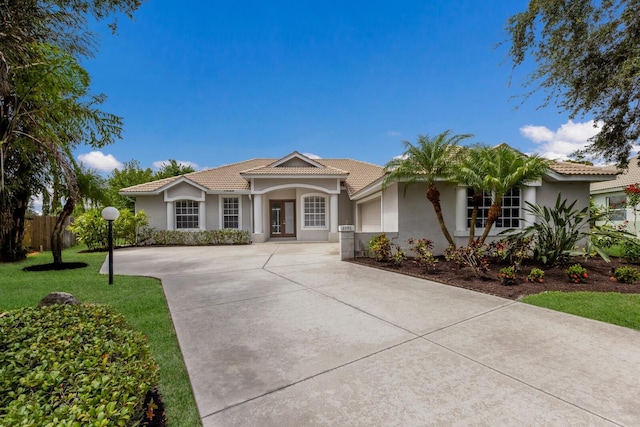 4998 Cedar Oak Way, Sarasota, FL 34233 - mediterranean / spanish-style home featuring concrete driveway, stucco siding, a garage, and a tile roof