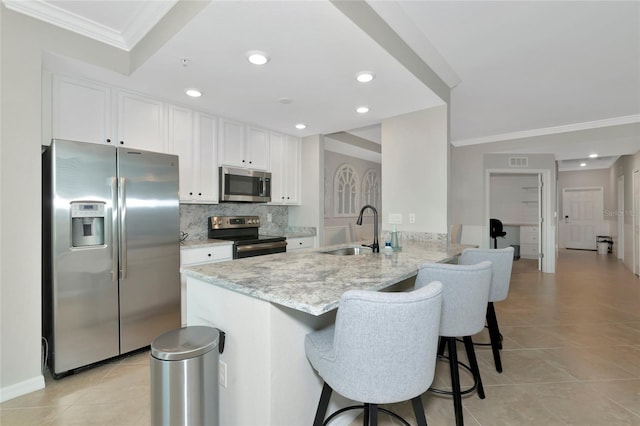 5604 Palmer Cir Unit 103, Bradenton, FL 34211 - kitchen featuring appliances with stainless steel finishes, ornamental molding, a breakfast bar area, light tile patterned floors, and white cabinets