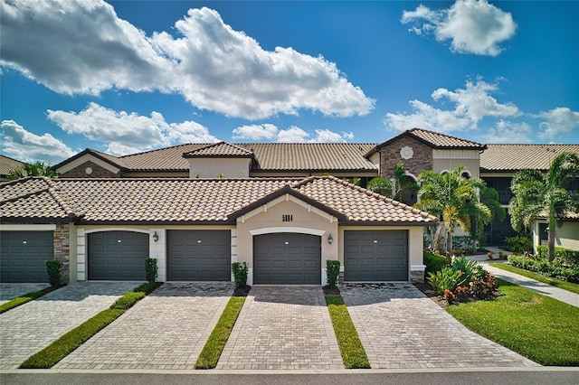 5604 Palmer Cir Unit 103, Bradenton, FL 34211 - view of front of house featuring a tiled roof, stucco siding, stone siding, and community garages
