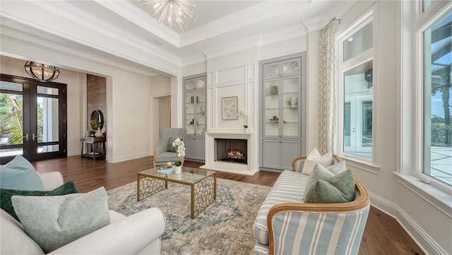 14665 Como Cir, Lakewood Ranch, FL 34202 - living area featuring a chandelier, a warm lit fireplace, wood finished floors, crown molding, and french doors