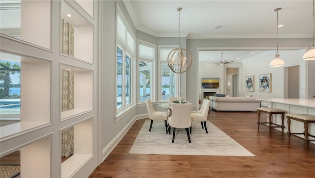 14665 Como Cir, Lakewood Ranch, FL 34202 - dining space with a chandelier, dark wood-type flooring, crown molding, a large fireplace, and a ceiling fan