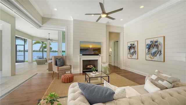 14665 Como Cir, Lakewood Ranch, FL 34202 - living room featuring ceiling fan, wood finished floors, crown molding, wood walls, and a large fireplace
