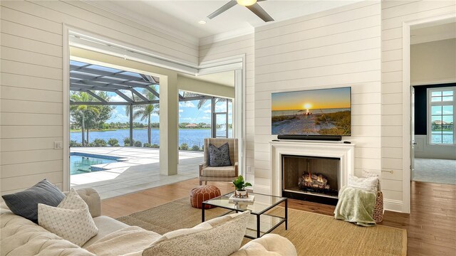 14665 Como Cir, Lakewood Ranch, FL 34202 - living area featuring wood finished floors, a ceiling fan, wood walls, a lit fireplace, and a sunroom