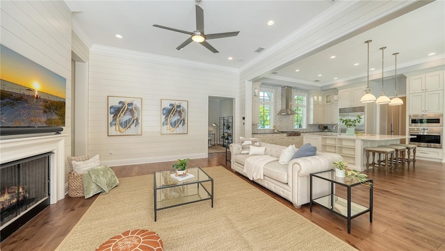 14665 Como Cir, Lakewood Ranch, FL 34202 - living room featuring crown molding, a fireplace, a ceiling fan, wood finished floors, and recessed lighting