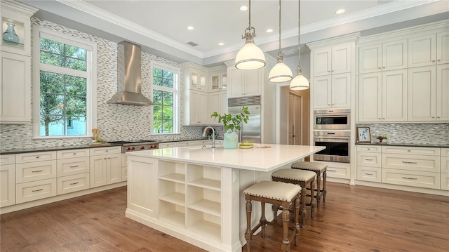 14665 Como Cir, Lakewood Ranch, FL 34202 - kitchen with wall chimney exhaust hood, stainless steel appliances, backsplash, dark wood-type flooring, and crown molding