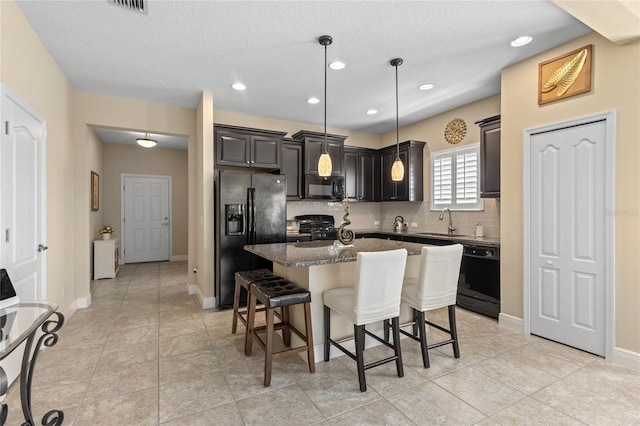 2070 Crystal Lake Trl, Bradenton, FL 34211 - kitchen with black appliances, tasteful backsplash, a kitchen island, a breakfast bar, and dark stone countertops