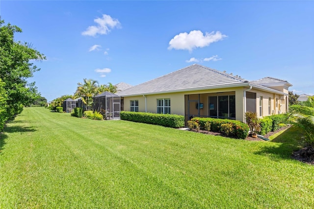 2070 Crystal Lake Trl, Bradenton, FL 34211 - rear view of property featuring a lawn, stucco siding, a sunroom, and a tiled roof