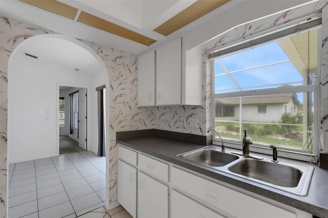1026 Graham Rd, Venice, FL 34293 - kitchen featuring dark countertops, wallpapered walls, white cabinetry, arched walkways, and light tile patterned floors
