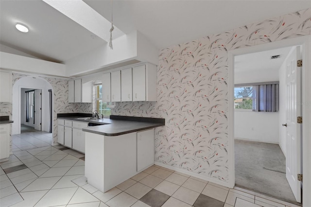 1026 Graham Rd, Venice, FL 34293 - kitchen featuring dark countertops, wallpapered walls, a peninsula, light tile patterned floors, and lofted ceiling