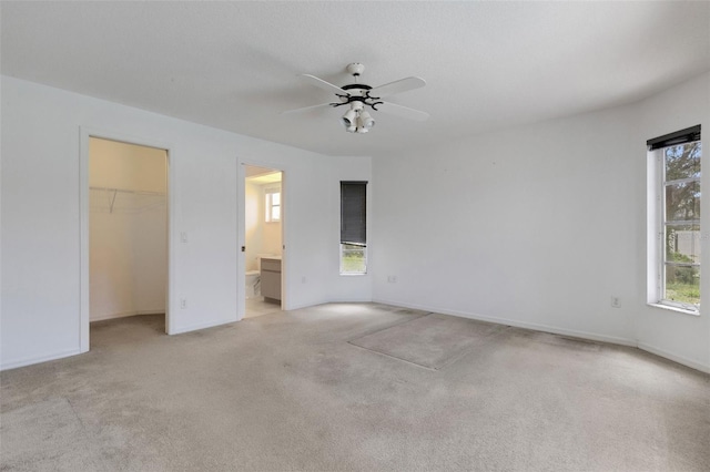 1026 Graham Rd, Venice, FL 34293 - unfurnished bedroom with light colored carpet, a walk in closet, connected bathroom, a ceiling fan, and a closet