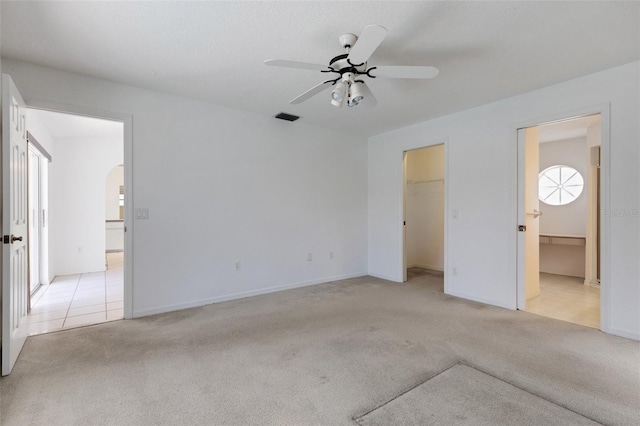 1026 Graham Rd, Venice, FL 34293 - unfurnished bedroom featuring light carpet, arched walkways, a walk in closet, connected bathroom, and ceiling fan