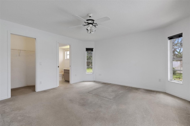 1026 Graham Rd, Venice, FL 34293 - unfurnished bedroom featuring multiple windows, light colored carpet, a spacious closet, and connected bathroom