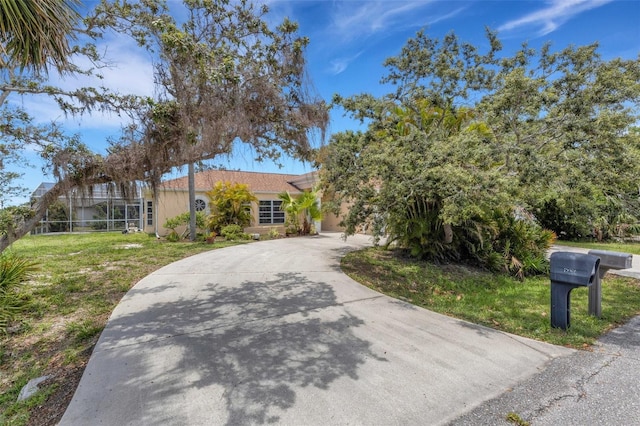 1026 Graham Rd, Venice, FL 34293 - view of front of house featuring stucco siding, concrete driveway, and a front lawn