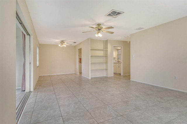 3276 Westford Ln, Sarasota, FL 34231 - empty room with ceiling fan, built in shelves, and light tile patterned floors