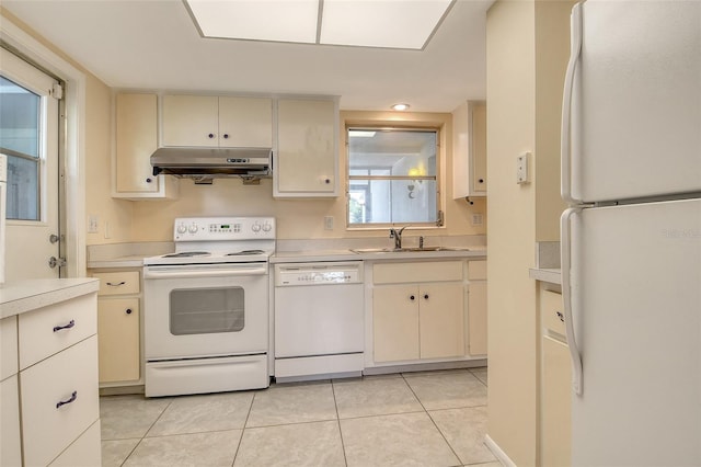 3276 Westford Ln, Sarasota, FL 34231 - kitchen with white appliances, under cabinet range hood, light countertops, light tile patterned floors, and cream cabinetry