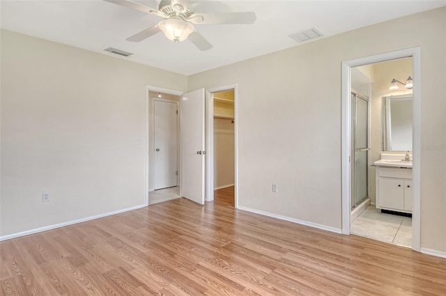 3276 Westford Ln, Sarasota, FL 34231 - unfurnished bedroom featuring light wood-style flooring, a walk in closet, a closet, ceiling fan, and ensuite bathroom