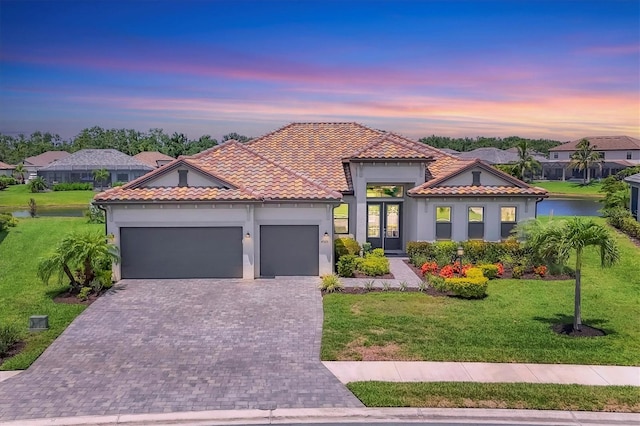 4925 Coastal Days Ln, Lakewood Ranch, FL 34211 - mediterranean / spanish-style home with a garage, decorative driveway, a yard, and stucco siding