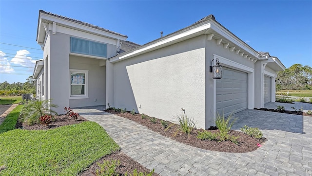 2321 Blue Mahoe Ln, Sarasota, FL 34240 - view of property exterior with a garage, stucco siding, central AC, and decorative driveway