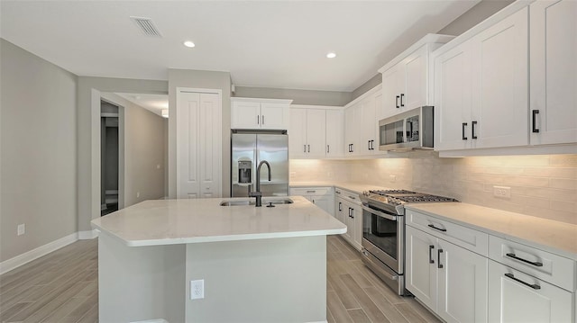 2321 Blue Mahoe Ln, Sarasota, FL 34240 - kitchen with appliances with stainless steel finishes, a sink, wood finish floors, backsplash, and recessed lighting