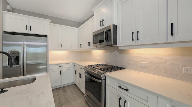 2321 Blue Mahoe Ln, Sarasota, FL 34240 - kitchen with appliances with stainless steel finishes, a sink, white cabinets, and backsplash