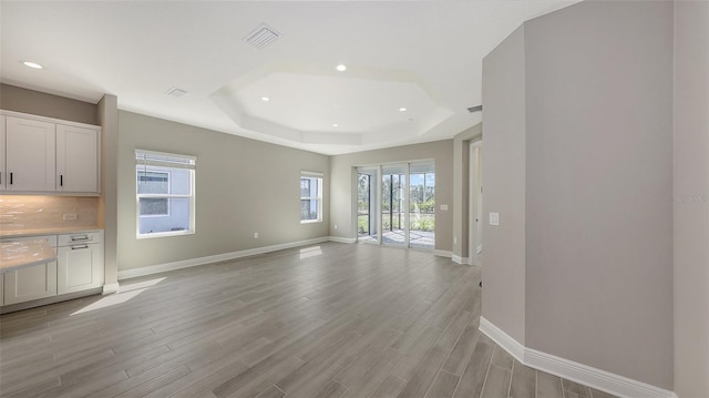 2321 Blue Mahoe Ln, Sarasota, FL 34240 - unfurnished living room with a tray ceiling, baseboards, light wood finished floors, and recessed lighting