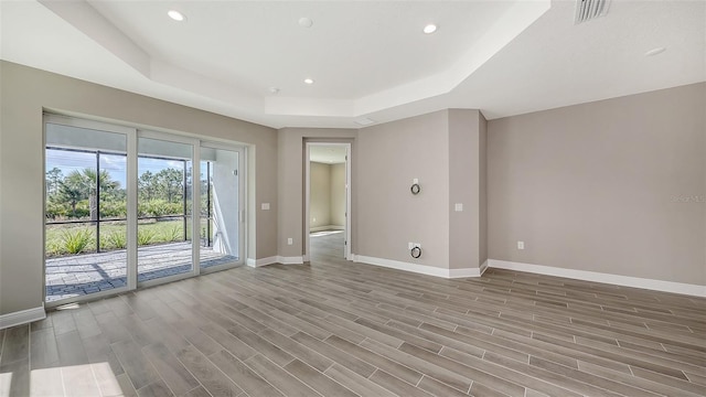 2321 Blue Mahoe Ln, Sarasota, FL 34240 - empty room with a tray ceiling, baseboards, recessed lighting, and wood finished floors