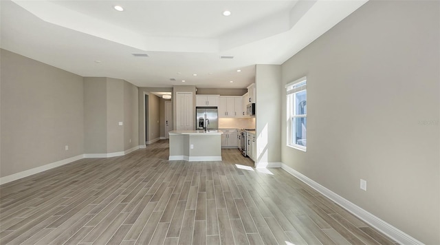 2321 Blue Mahoe Ln, Sarasota, FL 34240 - unfurnished living room featuring a tray ceiling, light wood finished floors, baseboards, and recessed lighting