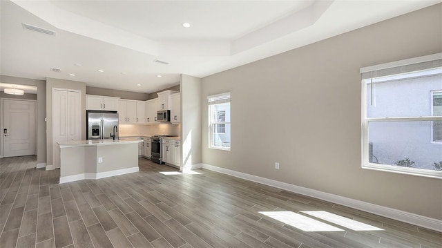 2321 Blue Mahoe Ln, Sarasota, FL 34240 - kitchen with appliances with stainless steel finishes, baseboards, light countertops, a center island with sink, and white cabinetry