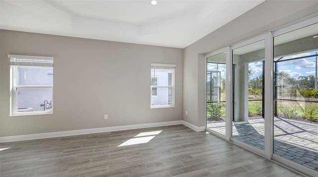 2321 Blue Mahoe Ln, Sarasota, FL 34240 - spare room featuring baseboards, wood finished floors, and a tray ceiling