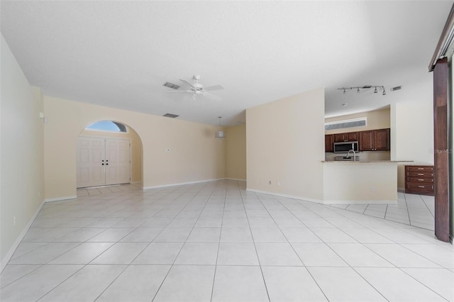 5410 Matthew Ct, Sarasota, FL 34231 - unfurnished living room with rail lighting, ceiling fan, arched walkways, and light tile patterned floors