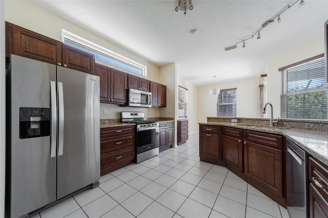 5410 Matthew Ct, Sarasota, FL 34231 - kitchen featuring appliances with stainless steel finishes, light tile patterned floors, hanging light fixtures, a textured ceiling, and dark brown cabinetry