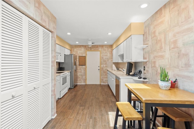 4637 Willow Wood Cir Unit 44, Sarasota, FL 34241 - kitchen with white appliances, light countertops, recessed lighting, white cabinets, and wood finished floors