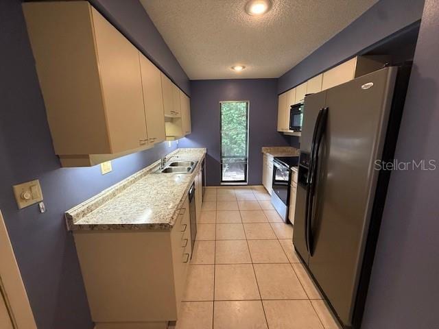 5032 81st Avenue Terrace E, Sarasota, FL 34243 - kitchen with black appliances, a textured ceiling, white cabinets, light countertops, and light tile patterned flooring