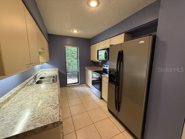 5032 81st Avenue Terrace E, Sarasota, FL 34243 - kitchen featuring fridge with ice dispenser, stainless steel range with electric stovetop, black microwave, a textured ceiling, and light tile patterned floors