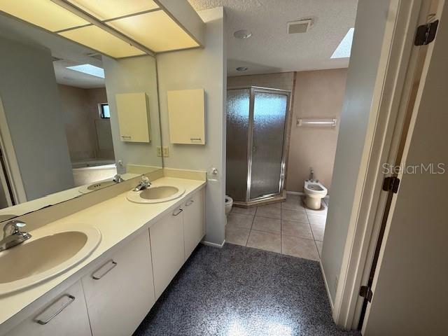 5032 81st Avenue Terrace E, Sarasota, FL 34243 - full bathroom featuring a shower stall, double vanity, a skylight, a bidet, and a textured ceiling