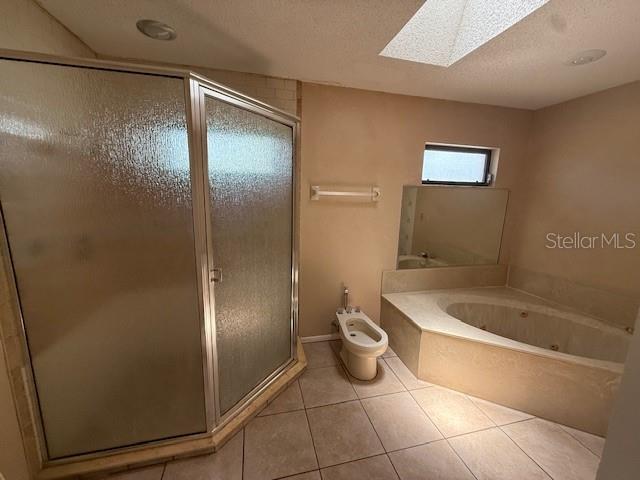 5032 81st Avenue Terrace E, Sarasota, FL 34243 - full bathroom featuring a skylight, a shower stall, a whirlpool tub, a bidet, and tile patterned flooring