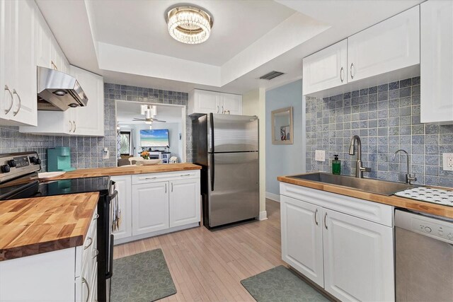 1500 Sunset Rd Unit B4, Tarpon Springs, FL 34689 - kitchen featuring wood counters, stainless steel appliances, range hood, light wood-type flooring, and tasteful backsplash