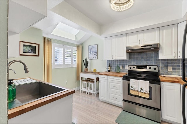1500 Sunset Rd Unit B4, Tarpon Springs, FL 34689 - kitchen with stainless steel range with electric stovetop, butcher block countertops, under cabinet range hood, decorative backsplash, and light wood-style flooring