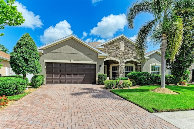 5307 65th Ter E, Ellenton, FL 34222 - view of front facade featuring stucco siding, stone siding, a garage, decorative driveway, and a front lawn