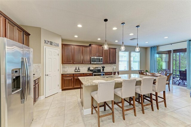 5307 65th Ter E, Ellenton, FL 34222 - kitchen with appliances with stainless steel finishes, backsplash, light stone countertops, recessed lighting, and a center island with sink