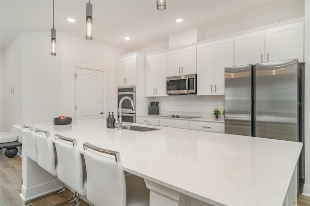 2108 Citrus Breeze Dr, Bradenton, FL 34208 - kitchen featuring appliances with stainless steel finishes, a spacious island, wood finished floors, white cabinets, and hanging light fixtures
