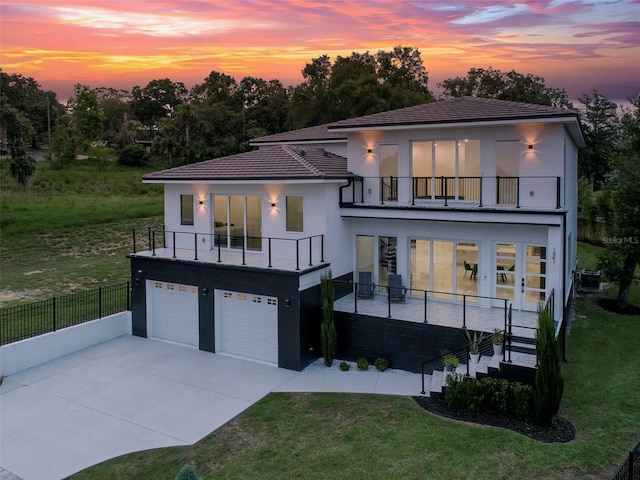 1841 Moorings Ct, Clermont, FL 34711 - back of property at dusk with a balcony, stucco siding, an attached garage, stairway, and driveway