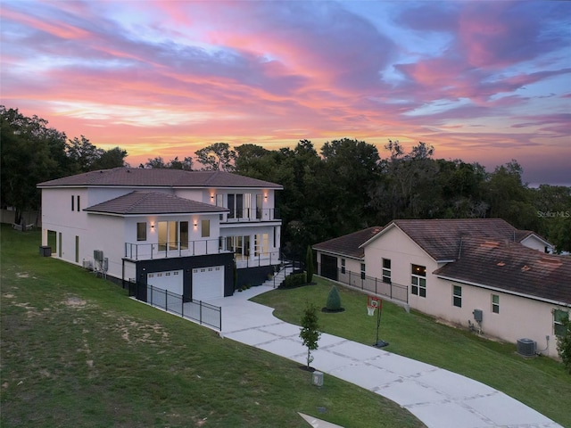 1841 Moorings Ct, Clermont, FL 34711 - back of property at dusk featuring a balcony, stucco siding, an attached garage, a lawn, and concrete driveway