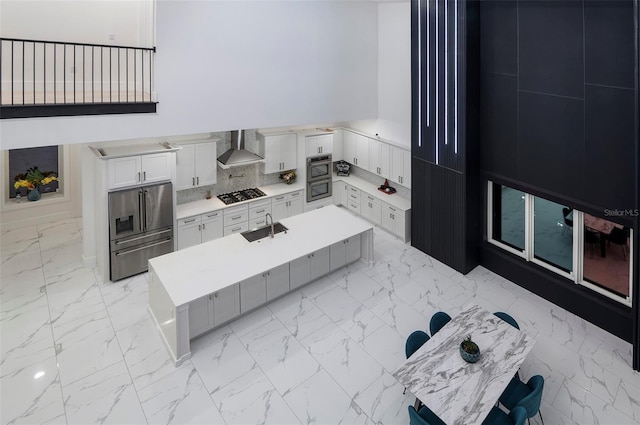 1841 Moorings Ct, Clermont, FL 34711 - kitchen featuring wall chimney range hood, appliances with stainless steel finishes, light marble finish flooring, light countertops, and an island with sink