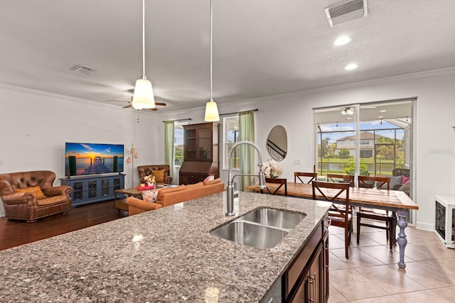 4617 Garden Arbor Way, Bradenton, FL 34203 - kitchen featuring a sink, crown molding, decorative light fixtures, open floor plan, and stone counters