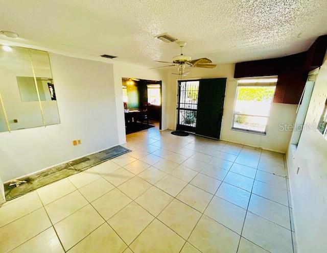 2607 29th Ave W, Bradenton, FL 34205 - empty room with light tile patterned flooring, ceiling fan, and a textured ceiling